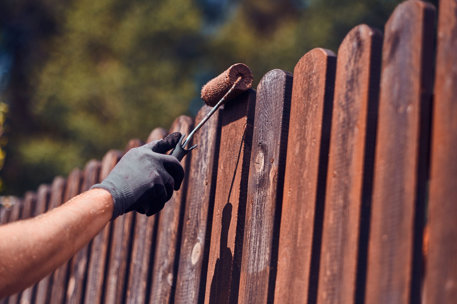 diligent man is painting fence with brush
