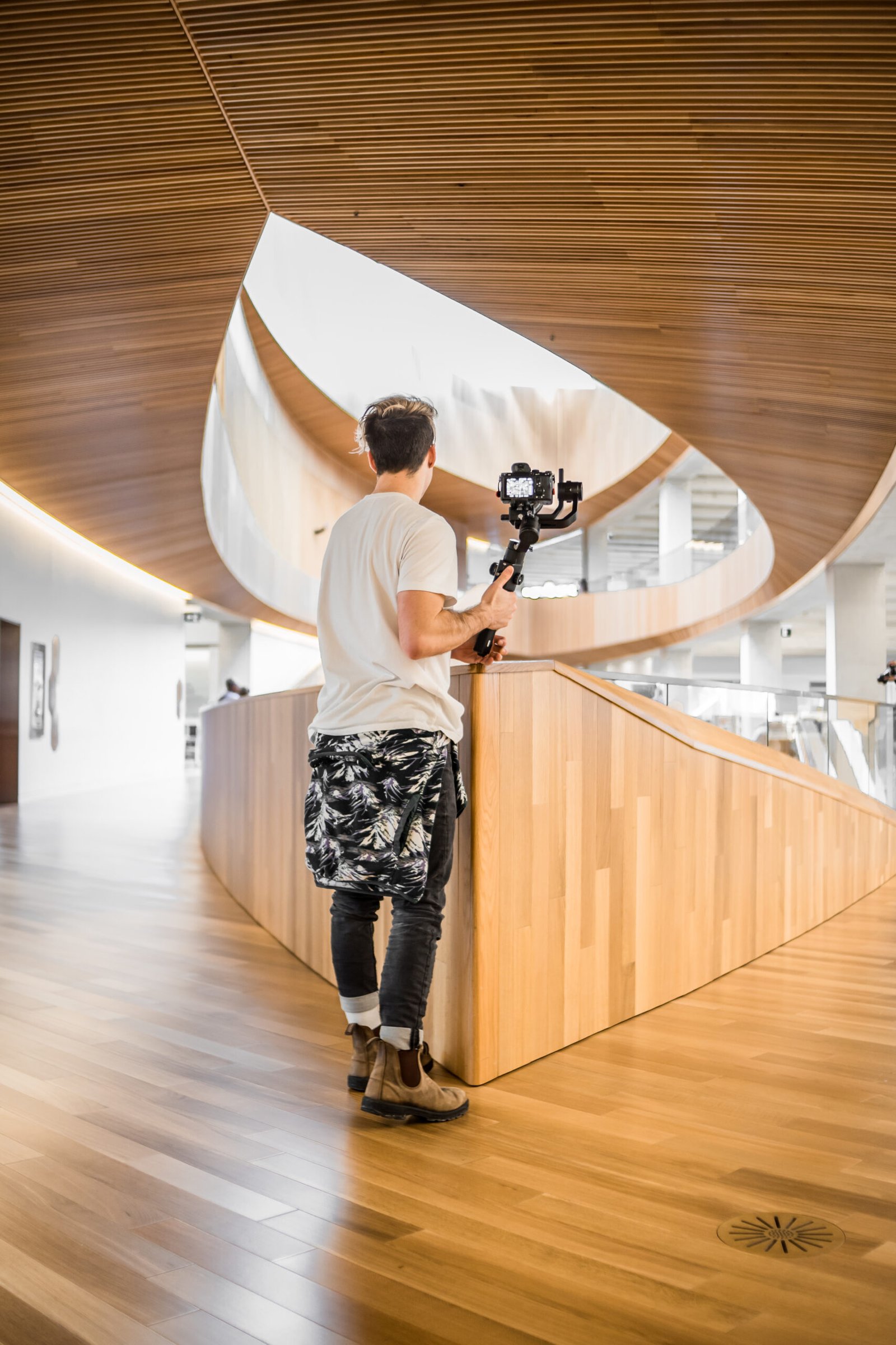 man in white t shirt and black and white pants holding black dslr camera